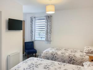 a bedroom with two beds and a blue chair at No 8 Cottage in Aviemore