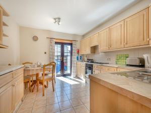 a kitchen with wooden cabinets and a table and chairs at Eryb Cottage - Uk46883 in Kilmory