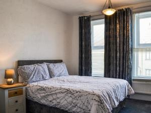 a bedroom with a bed and two windows at The Apartment in Filey