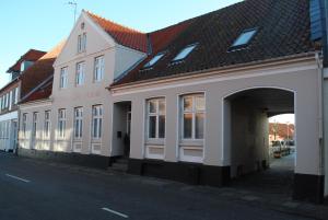 ein weißes Gebäude mit einem Torbogen auf einer Straße in der Unterkunft Det Lille Hotel in Rønne