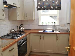 a kitchen with white cabinets and a sink and a window at 9 Howrah's Court in Keswick