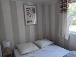 a bed with two pillows in a room with a window at Mobil-home à 11km d'Europa Park via le bac in Boofzheim