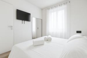 a white bedroom with a bed with a tv on it at Jacuzzi Luxury Suite Iseo Elegant Apartment with Balcony Central Iseo in Iseo