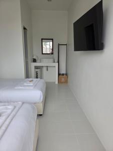 a white room with two beds and a flat screen tv at Treat Boutique HuaHin 94 in Hua Hin