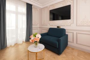 a living room with a blue chair and a vase of flowers at Mode Paris Aparthotel in Paris