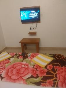 a room with a bed with a flower blanket and a tv at Naksh Villa in Mahabaleshwar