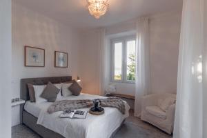 a bedroom with a large bed and a chair at Villa Elisabetta Lago Maggiore in Belgirate