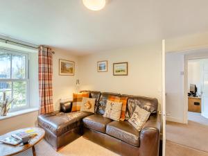 a living room with a leather couch and a table at Court End Cottage in Silecroft