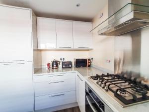 a kitchen with white cabinets and a stove top oven at Mont Blanc House in Braunton +12 photos
