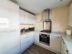a kitchen with white cabinets and a stove top oven at Mont Blanc House in Braunton