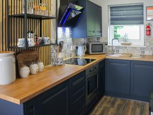 una cucina con armadi blu e ripiano in legno di Tyglyn Cottage a Lampeter