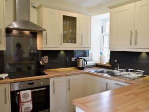 a kitchen with white cabinets and a sink at Straitinnan in Haugh of Glass