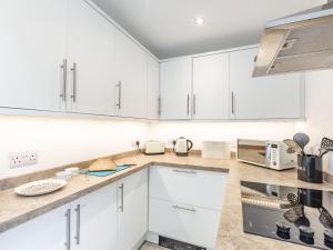 una cucina bianca con armadietti e elettrodomestici bianchi di Quince Cottage a Flookburgh