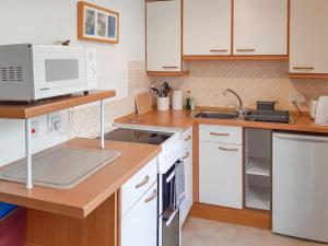 eine Küche mit weißen Schränken und einer Mikrowelle in der Unterkunft Atlantic Retreat in Padstow