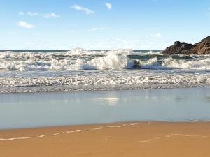 eine Welle im Meer an einem Sandstrand in der Unterkunft Atlantic Retreat in Padstow + 3 Fotos