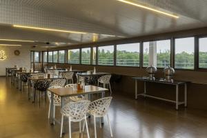 a dining room with tables and chairs and windows at River Splash Resort,Karjat in Neral