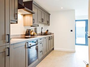 eine Küche mit Holzschränken und Geräten aus Edelstahl in der Unterkunft Hafan Gwyn - Cottage in Verwick