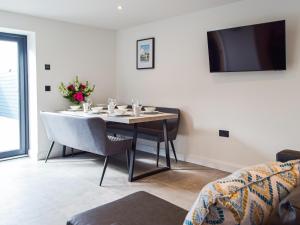 ein Esszimmer mit einem Tisch mit Stühlen und einem TV in der Unterkunft Hafan Gwyn - Cottage in Verwick