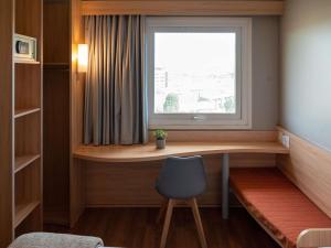 a room with a desk and a window with a chair at ibis Concepcion in Concepción