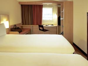 a hotel room with a white bed and a chair at ibis Antofagasta in Antofagasta