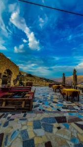 a patio with tables and chairs and a blue sky at Mumia heritage restaurant & house in Kerak +10 photos