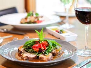 a plate of food on a table with a glass of wine at Mercure Hunter Valley Gardens in Pokolbin
