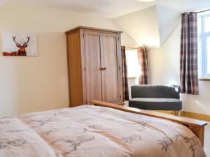 a bedroom with a bed and a chair at West Lanegate Farmhouse in Amisfield Town