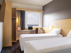 a hotel room with two beds and a desk with a computer at Ibis Chihuahua in Chihuahua