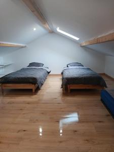 zwei Betten in einem großen Zimmer mit Holzboden in der Unterkunft Dépendance meublée avec terrasse in Carbon-Blanc