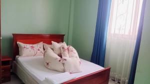 a bedroom with a bed with pillows and a window at Intent Suites in Kampala