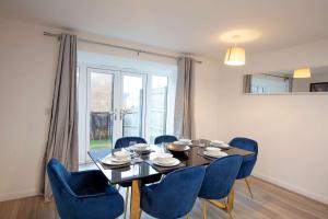 a dining room with a table and blue chairs at Bright & Modern 4 Bedroom House in Yeovil in Over Compton