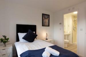 a bedroom with a bed and a bathroom with a toilet at Bright & Modern 4 Bedroom House in Yeovil in Over Compton +28 photos