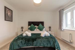 a bedroom with a large green bed with two pillows at Bright & Modern 4 Bedroom House in Yeovil in Over Compton