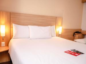 un grande letto con cuscini bianchi e una rivista sopra di ibis Lima Larco Miraflores a Lima