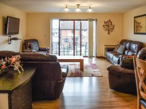 een woonkamer met leren banken en een tafel bij Swift Cottage in Horning