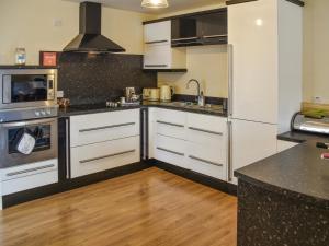 een keuken met witte kasten en roestvrijstalen apparaten bij Swift Cottage in Horning