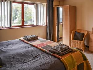 een slaapkamer met een bed met een deken erop bij Swift Cottage in Horning