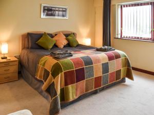 een slaapkamer met een bed met een kleurrijke deken bij Swift Cottage in Horning +33 foto's