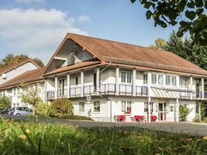 a large white building with a brown roof at ibis Kassel Melsungen in Melsungen