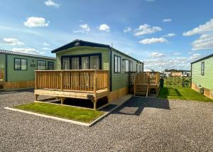 a green caravan with a porch and a bench at Burtree Lakes Holiday Park in Bedale