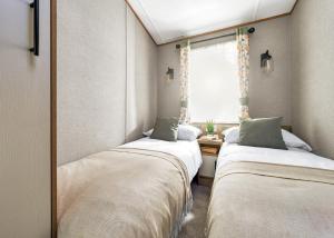 two beds in a small room with a window at Burtree Lakes Holiday Park in Bedale