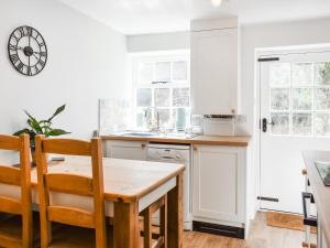 a kitchen with white cabinets and a wooden table at Causeway Cottage in Wolsingham