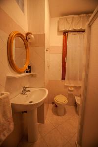 Un baño con lavabo, inodoro y espejo. en Cozy apartment near the beach, en Rosolina Mare