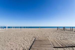 una playa de arena con un paseo marítimo de madera y el océano en Cozy apartment near the beach, en Rosolina Mare 9 fotos más