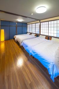 two beds in a room with wood floors and windows at Yunosawa HOUSE in Kusatsu
