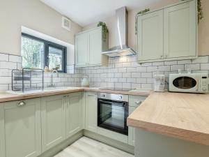 Una cocina con gabinetes blancos y un microondas. en Wisteria Cottage, en South Cerney