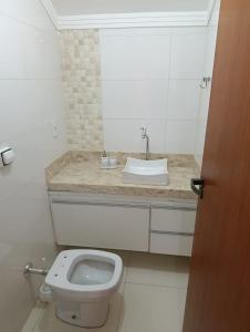 a white bathroom with a sink and a toilet at Apartmento duplex in Araxá +13 photos