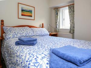 un letto blu e bianco con due asciugamani sopra di Ivy Cottage a Settle Altre 6 foto