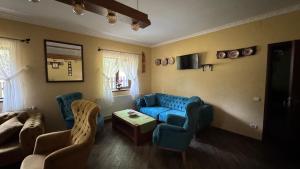 a living room with a blue couch and chairs at Conacul Dascălu Valea Doftanei in Trăisteni