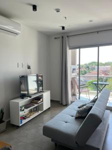 Una sala de estar con un sofá y un televisor. en TR Recoleta, en Asunción